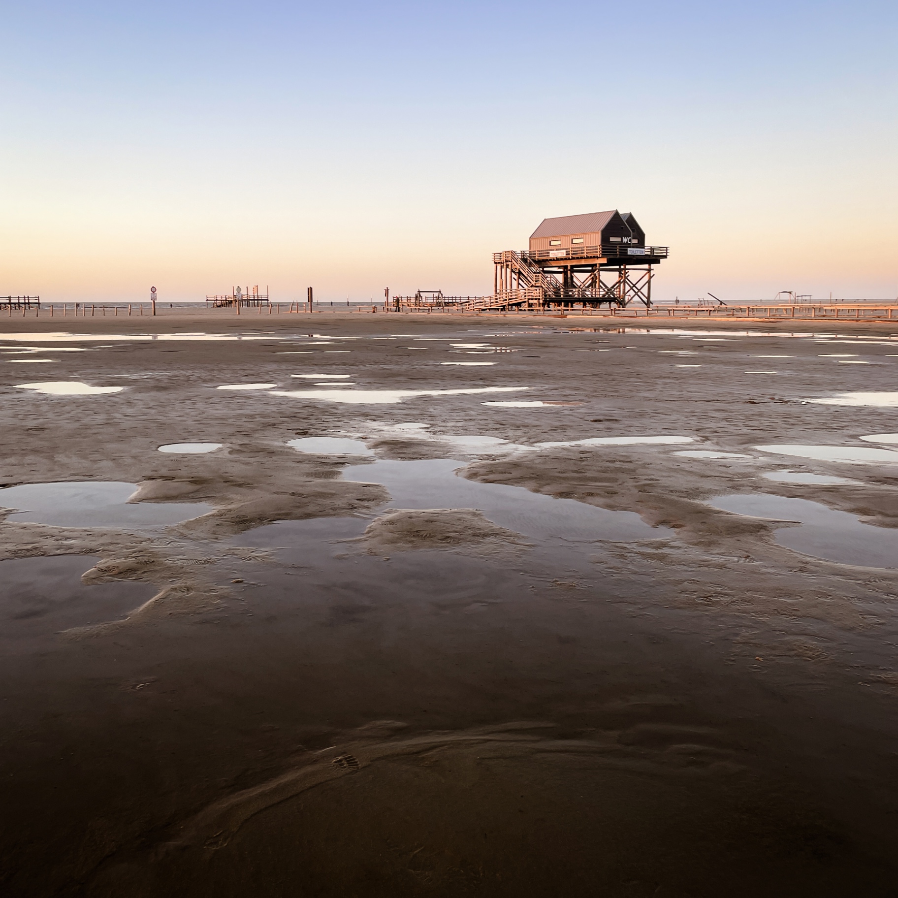 St. Peter-Ording auf Holz - Pfahlbau im Morgenlicht mit Wattpfützen